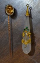 A teardrop shaped moonstone drop pendant with a yellow metal cap, and flower stems attached, with th