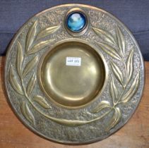 An Arts and Crafts embossed brass wall charger, inset a glazed ceramic "Ruskin" roundel, 36cm diamet