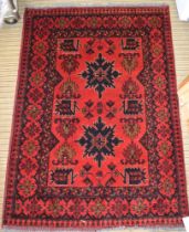 A red ground Persian rug with stylized motifs, fringed & bordered, 144cm x 102cm