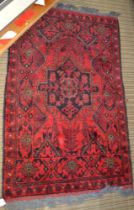 A Persian crimson ground small rug, decorative device to centre, fringed & bordered, 127cm x 79cm