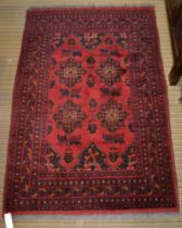 A Persian rug, four stylized floral designs on a red field, bordered & fringed, 154cm x 100cm
