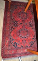 A Persian rug, with stylized motifs on a red field, bordered & fringed, 160cm x 103cm