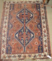 A Persian design rug, central motif on blue ground, laid upon a terracotta ground with stylized plan