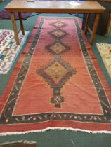 A large red ground loosely woven long rug with four central diamond motifs 156 x 388 cm