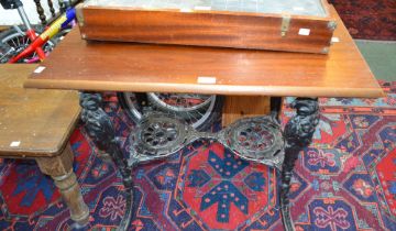 A cast metal framed pub table with mask decoration and polished wood top