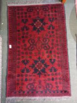 A small dark red woven woollen hearth rug