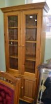 A modern pine display cabinet, two glazed doors over two cupboard doors