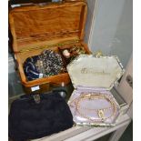 A wooden jewellery box containing costume jewellery with a cocktail purse