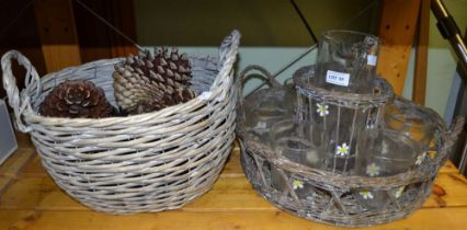 A woven tray containing "Daisey" lemonade set and a twin handled basket containing large pine cones