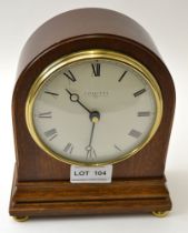 A "Comitti" mahogany cased mantel clock raised on brass bun feet, circular dial with Roman numerals,