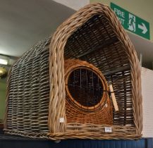 An open ended wicker dog kennel with a wicker cat basket