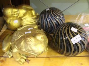 A gold painted garden frog with a buddha and two ornamental balls