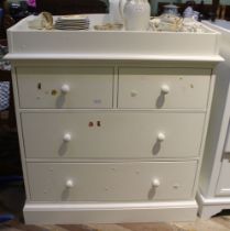A modern white melamine baby changing unit, two short over two long drawers