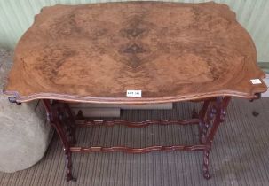 An Edwardian centre table, shaped walnut veneer top, on decorative trestle ends with castors, 75cm x