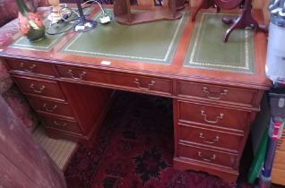 A reproduction mahogany twin pedestal writing desk, top inset tooled green leather panels, fitted br
