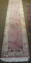 A pink ground floral & fringed bordered hall runner, 305cm