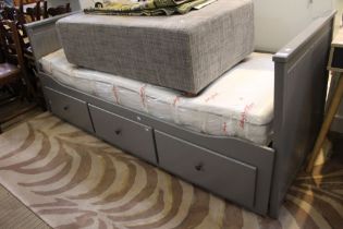A modern grey painted day bed, with three storage drawers beneath