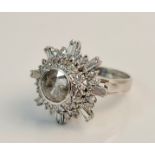 A stamped 18K 750 diamond cluster ring of flower design, central stone surrounded by a band of