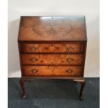 A walnut three drawer bureau on four Queen Anne style legs.