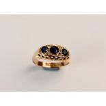 A hallmarked 9ct yellow gold three stone sapphire ring separated by diamond accents ( one stone