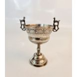 A two handled white metal engraved goblet with handles depicting Llamas.