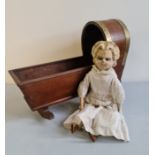 A 19th century doll with paper mache head wood arm and legs and a cloth body with a mahogany crib.