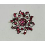 A garnet open metalwork floral design brooch, unmarked.
