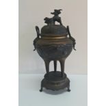 A Chinese bronze censer with dragon design on three long legs.