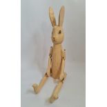 A hand carved large wooden rabbit with jointed arms and legs.