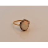 A hallmarked 9ct yellow gold opal and diamond cluster ring, set with an oval opal cabochon,