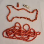 A coral beaded necklace with a two tone coral beaded necklace and two pendant charms