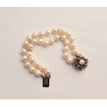 A double row cultured pearl bracelet with pearl and green gem clasp.