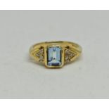 An 18ct yellow gold aquamarine and diamond ring, the central emerald cut aquamarine measuring