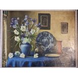 Oil on canvas depicting a still life with flowers in a vase with pictures to background. Signed with