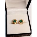 A pair of emerald and diamond earrings, each set with an oval cut emerald and four round brilliant