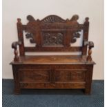 A oak monks bench with carving to base and back.