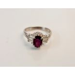 A ruby and diamond cluster ring, set with a central oval cut ruby surrounded by round brilliant