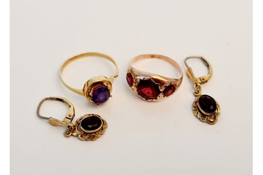 A yellow metal ring of three graduated red stones, ring size K, and a yellow metal gem stone ring,