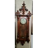 A walnut regulator wall clock with weights and pendulum.