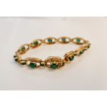 An emerald and diamond bracelet, each open metalwork oval design link set with a central oval cut