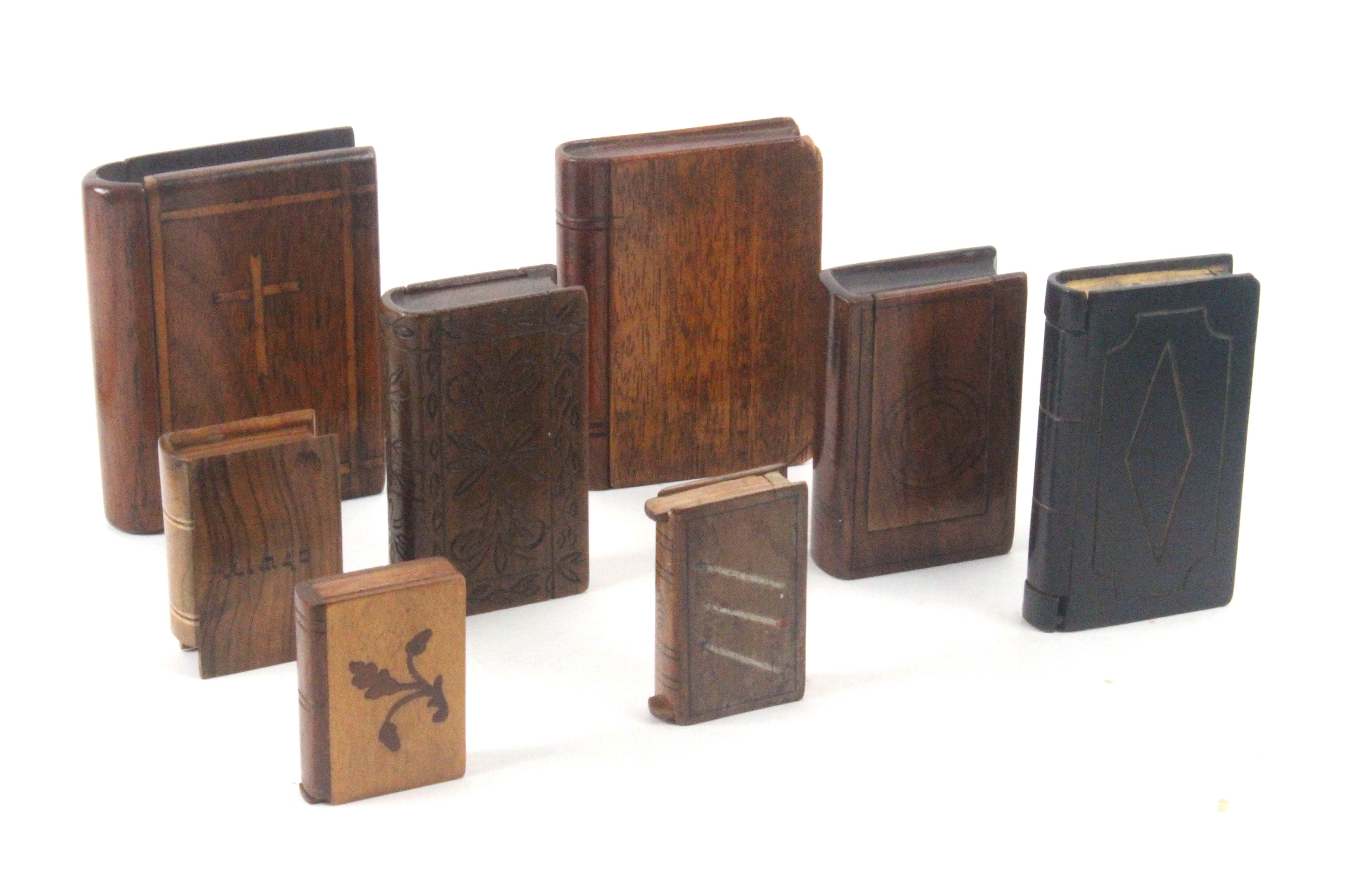 Eight book form wooden 'secret' boxes, comprising an early 19th Century hardwood example carved with