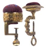 Two gilt brass sewing clamps, comprising a rectangular frame example below an oval pin cushion