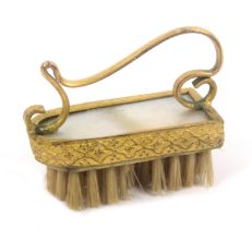 A Palais Royal mother of pearl and gilt metal mounted moustache brush, with scroll handle, 4.4cms.