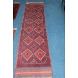 A modern Baluchi runner, midnight blue and madder red, with hooked medallions and kilim ends, 60cm x