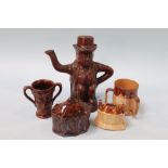A 19th century treacle glazed pottery teapot, a bacchanal two handle vessel, a brown glazed money