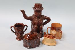 A 19th century treacle glazed pottery teapot, a bacchanal two handle vessel, a brown glazed money