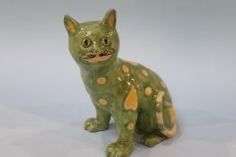 An Emile Galle style pottery cat, with glass eyes, on green ground with yellow hearts, 20cm height