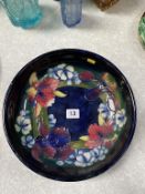 A Moorcroft shallow circular bowl, on dark blue ground, decorated with flowers, 27cm diameter