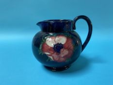 A Moorcroft jug on a dark blue ground, decorated with flowers