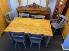 A pine kitchen table with six grey painted chairs